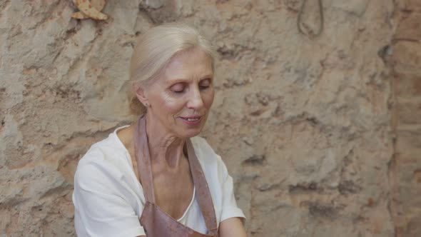 Senior Female Potter Sculpts a Clay Pot alt