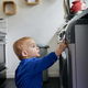 close up of toddler reaching up and touching appliance in kitchen - PhotoDune Item for Sale