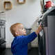 Toddler reaching up and touching appliance in kitchen - PhotoDune Item for Sale