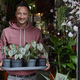 Portrait of man holding tray of plants in doorway of flower shop - PhotoDune Item for Sale