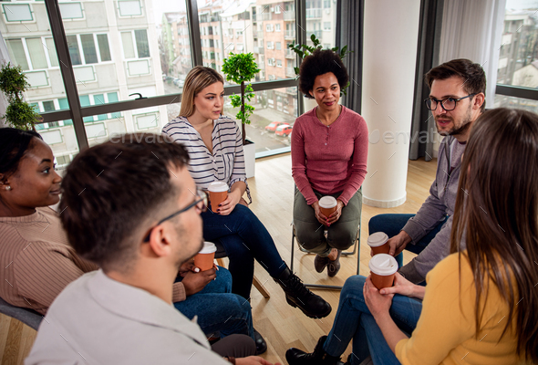 Diverse group of people sitting in circle in group therapy session ...