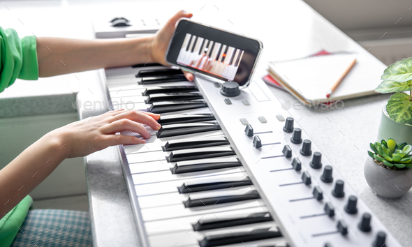 The child learns to play the piano with a smartphone, online music lesson.