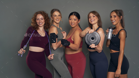 Five young women in sports clothes and gym accessories in studio shot Stock  Photo by gpointstudio