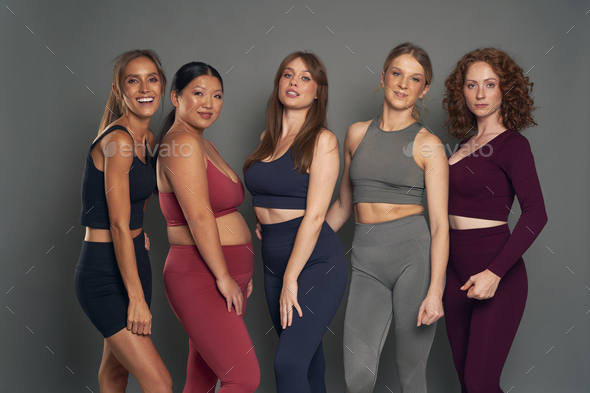 Five young women in sports clothes and gym accessories in studio shot Stock  Photo by gpointstudio