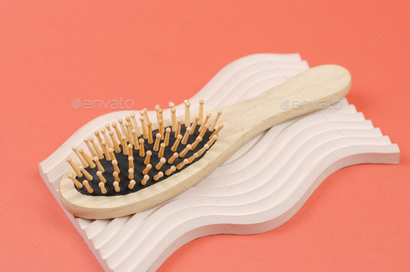 Hair brush made of natural material. Wooden hair combs on a beige plaster podium