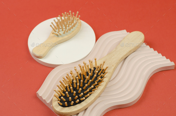 Hair brush made of natural material. Wooden hair combs on a beige plaster podium. Zero waste