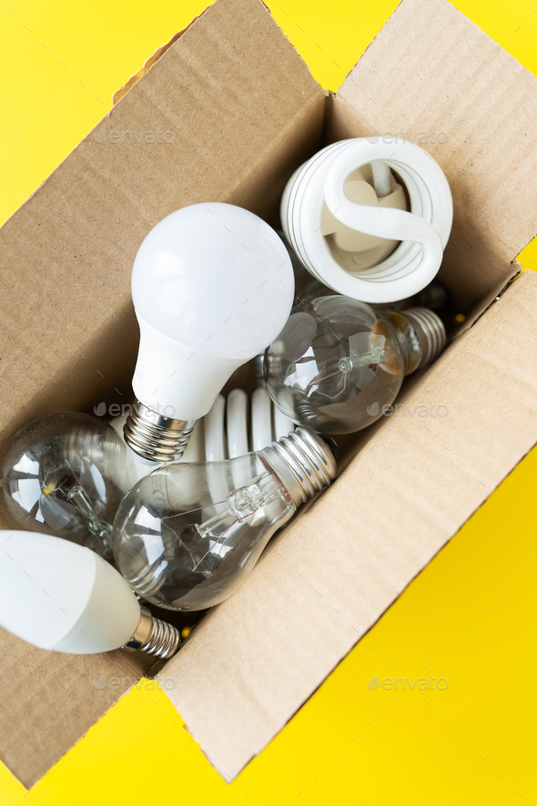 A set of different types of LED and incandescent lamps in a craft box on a yellow background.