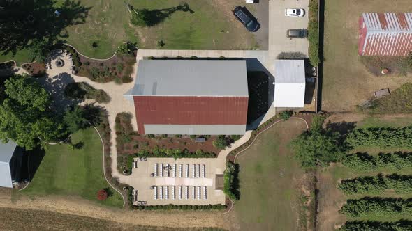 Aerial top down view of a wedding venue ceremony setup next to a barn at a farm in the countryside. alt