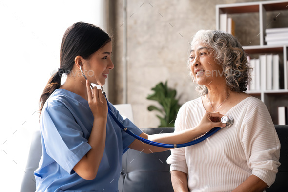 Young nurse listening to older woman lung or heart sound with stethoscope
