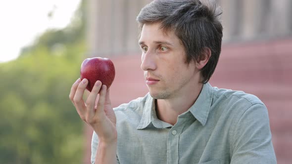 Young Millennial Man Wants to Eat Apple but Cannot alt