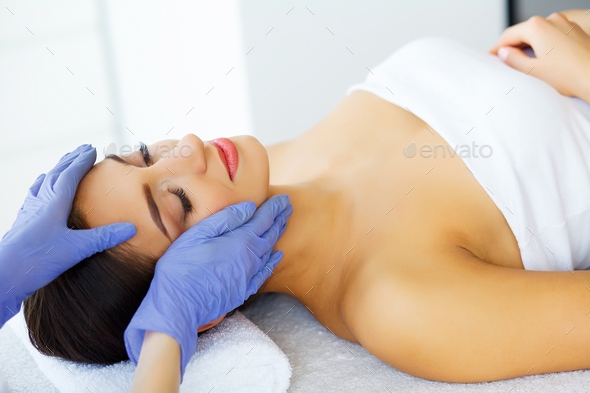 A beautiful woman gets a facial massage in a spa salon