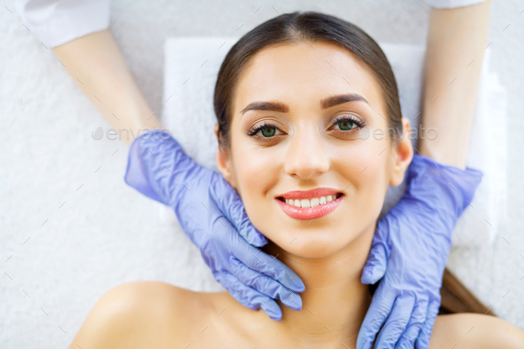 A beautiful woman gets a facial massage in a spa salon.