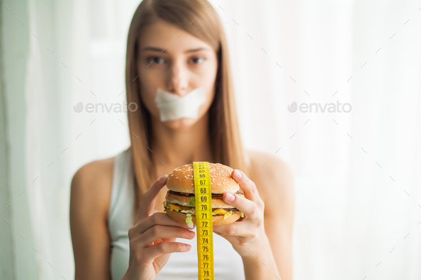 Young woman with duct tape over her mouth, preventing her to eat junk food
