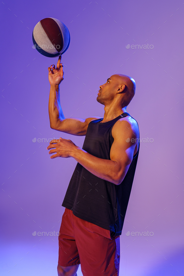 Professional basketball player spinning ball on his finger on studio  background Stock Photo by KostiantynVoitenko