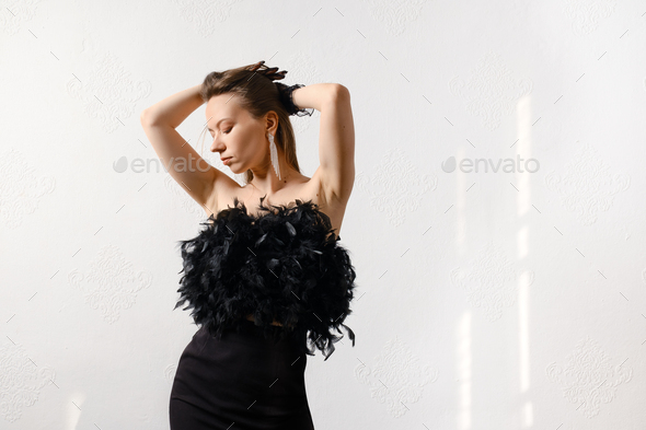 Stylish woman in corset with feathers with closed eyes