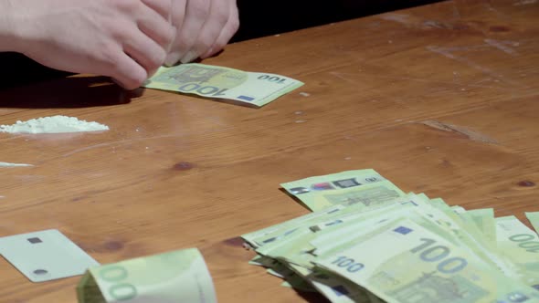 Drug Addict Rolls 100 Euro Banknote On The Table And Snort Powdered Cocaine Drug. close up alt