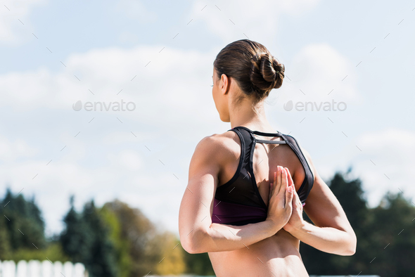 fit yogini in Reverse Prayer Pose practicing yoga outdoors
