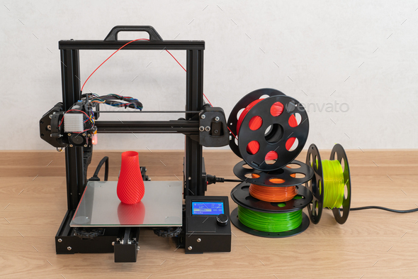 Modern 3D printer and multi-colored filament spools - Stock Photo - Images