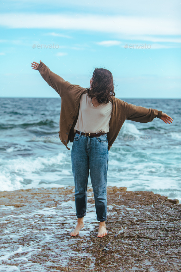 Land koppeling lade woman walking by rocky beach in wet jeans barefoot Stock Photo by  petruninsphotos