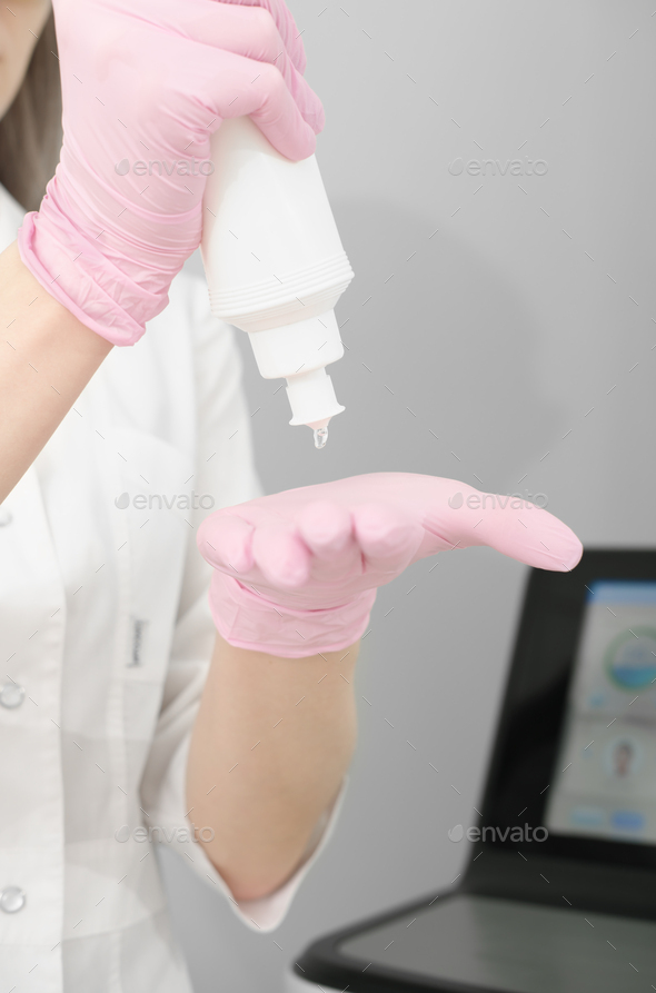 woman showing bottle with ultrasound guide gel for laser epilation procedure. drop of a gel on hand - Stock Photo - Images