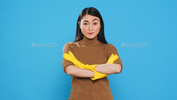 Asian professional maid smiling at camera after finishing house cleaning