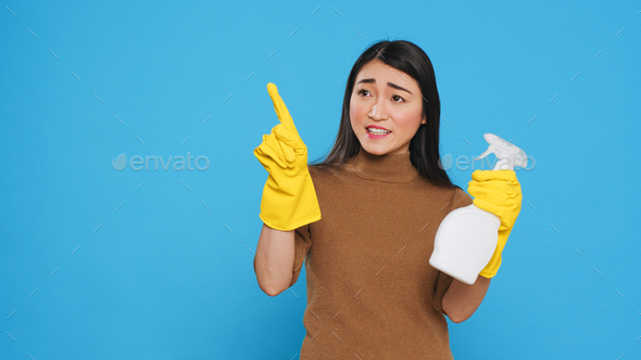 Professional maid pointing and showing cleaning product or isolated text