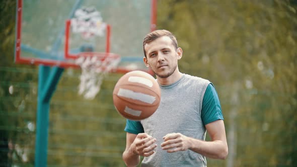 A Man Standing on a Sports Ground and Throws Up the Basketball Ball alt