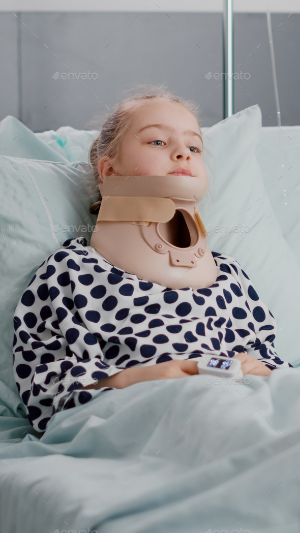 Portrait of sick child patient lying in bed looking at camera while having neck cervical collar
