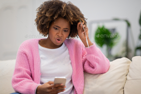 Shocked black woman looking at phone screen, copy space