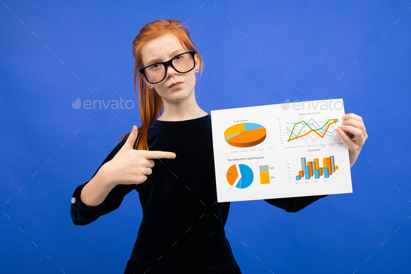 smart teenager girl in glasses and a black dress shows statistics with pie charts and graphs on a
