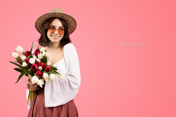 Happy pretty young caucasian woman in casual, hat and glasses with flower  bouquet, enjoy birthday Stock Photo by Prostock-studio