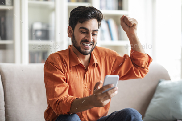 Emotional middle eastern man using smartphone and gesturing