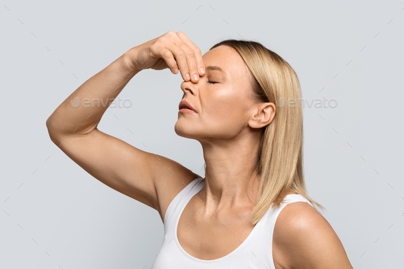 Blonde woman touching nose, suffering from bleeding