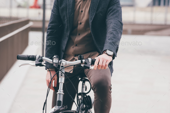 Unrecognizable contemporary stylish businessman going to work by bike commuting the carbon-free way