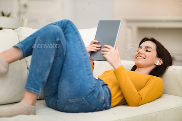 Relaxed young woman chilling on couch at home, watching movie