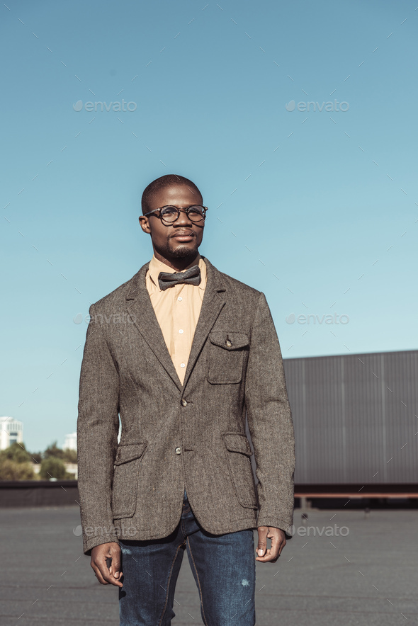 Handsome african american man in tweed jacket and glasses, standing in ...
