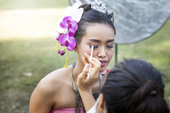 Make up artist making up eye liner to Thai woman wearing thai traditional clothing
