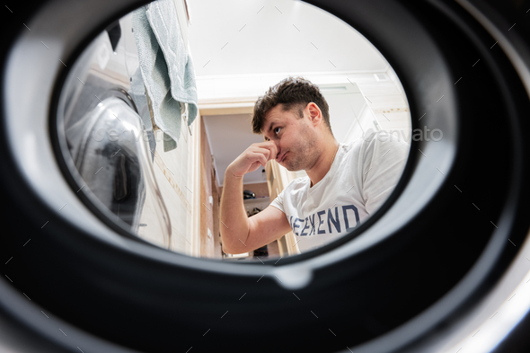 Man view from washing machine inside. Male does laundry daily routine.