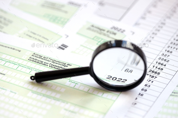 German different tax forms and magnifying glass pointed on 2022 inscription - Stock Photo - Images