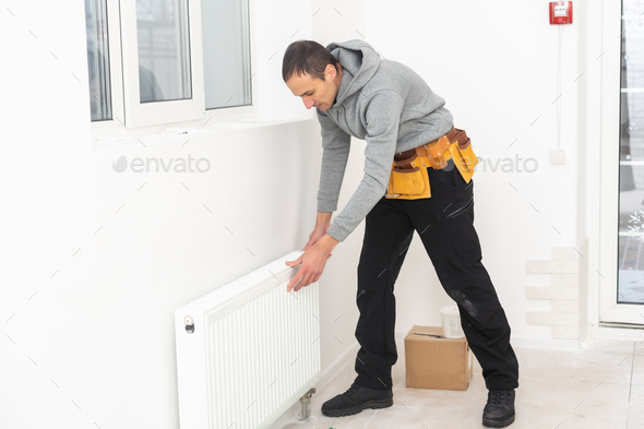 Man is repairing radiator battery in the room. Maintenance repair works renovation in the flat