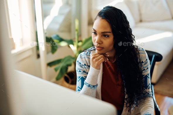 Young black woman working on desktop PC at home.