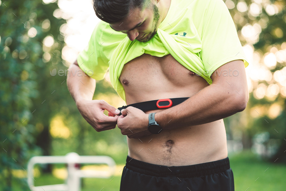 Man setting his waist band to measure his pulse white working out Stock  Photo by Visual__Production