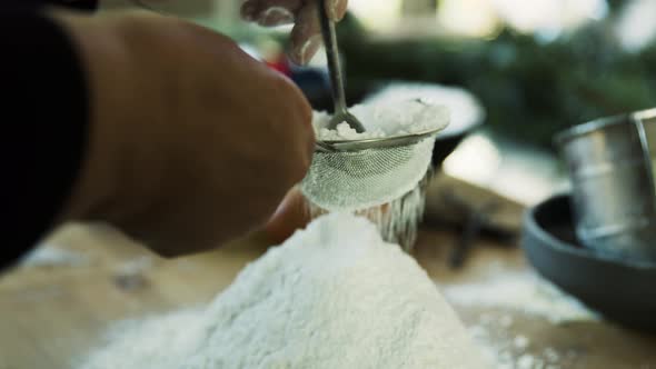 Woman sieving flour for cookie dough alt