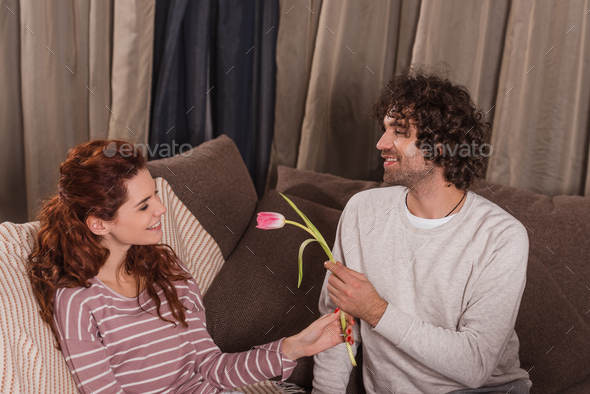 smiling boyfriend presenting tulip to girlfriend