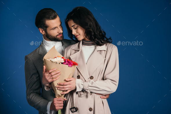 boyfriend presenting bouquet to girlfriend isolated on blue
