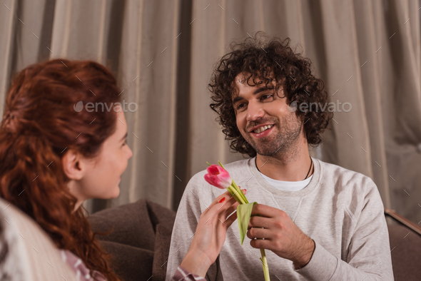 smiling boyfriend presenting tulip to girlfriend