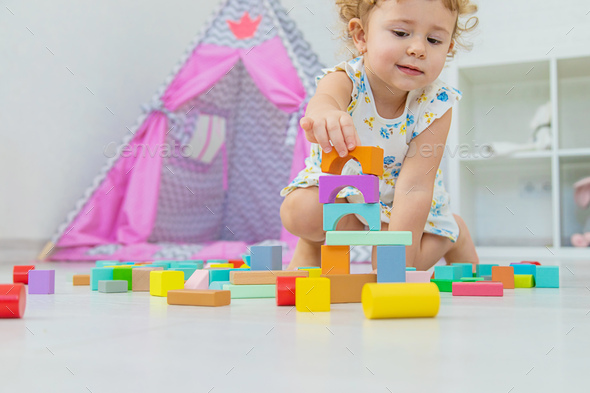 The child plays in the children\'s room with a wooden constructor. Selective focus.