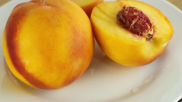 Beautiful juicy cut peach fruit with stone rotates on a white background. Eco fruit summer season