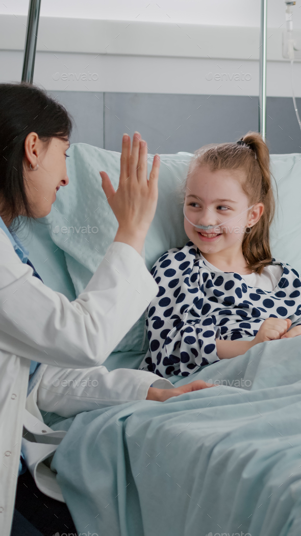 Pediatric woman doctor interacting with sick patient giving high five ...