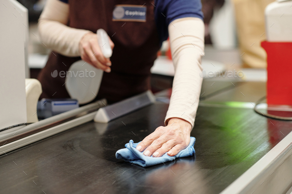 Close-up of cashier bending over checkout line in supermarket